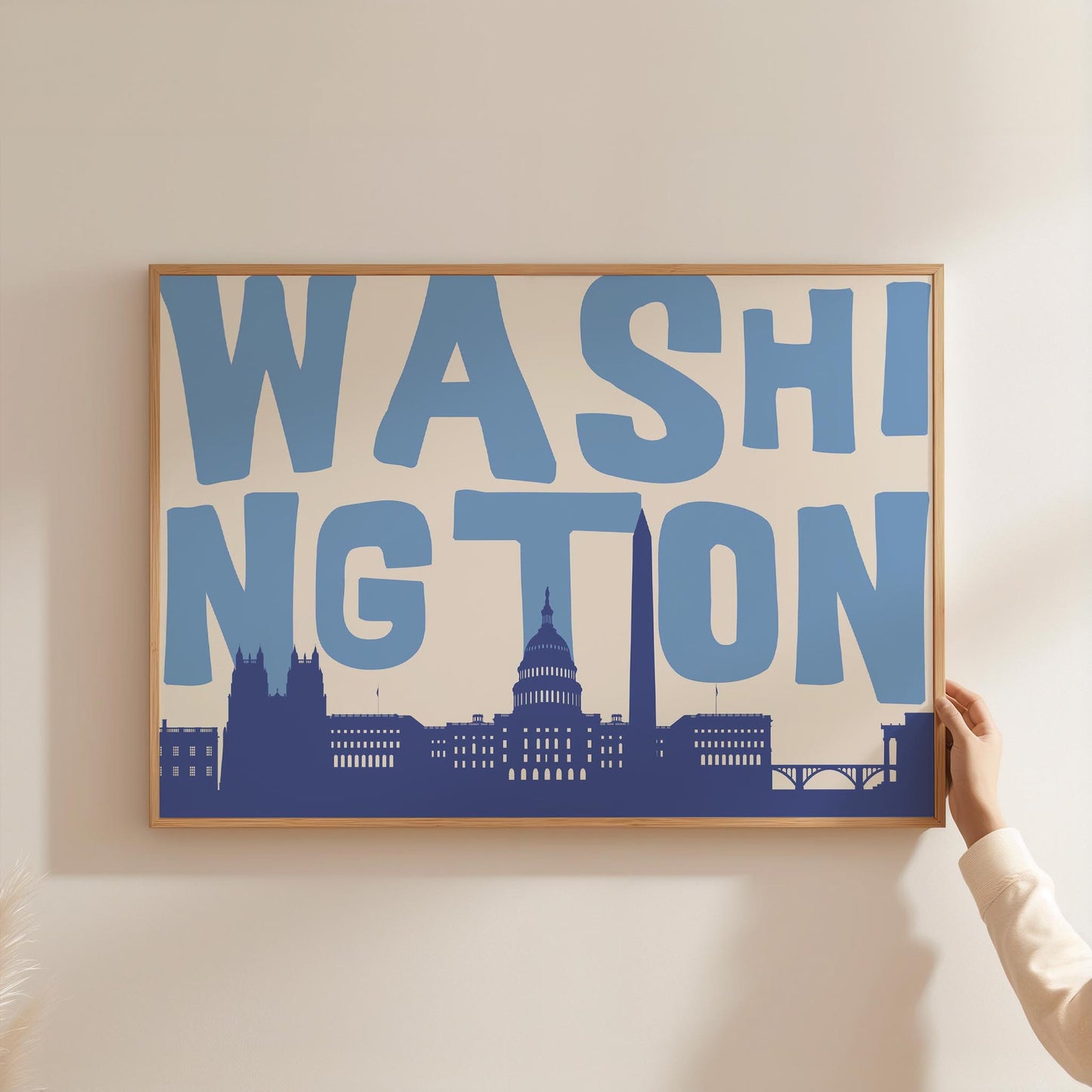 A modern graphic print of the Washington DC skyline, including the Capitol Building. The word 'WASHINGTON' is in large blue letters above the cityscape.