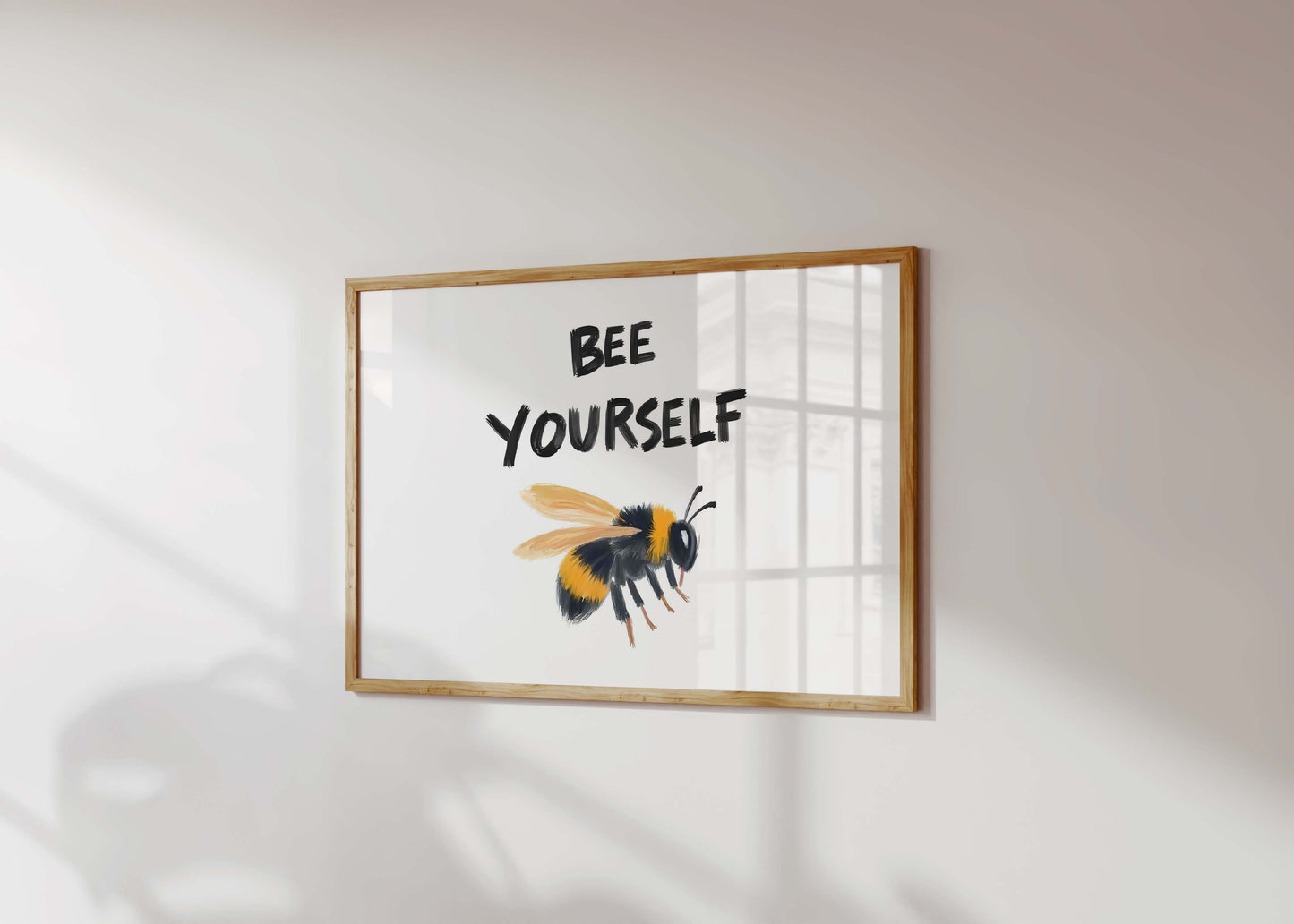 An inspirational bee print in a landscape frame, featuring a painterly bumblebee illustration under the quote 'Bee Yourself'.