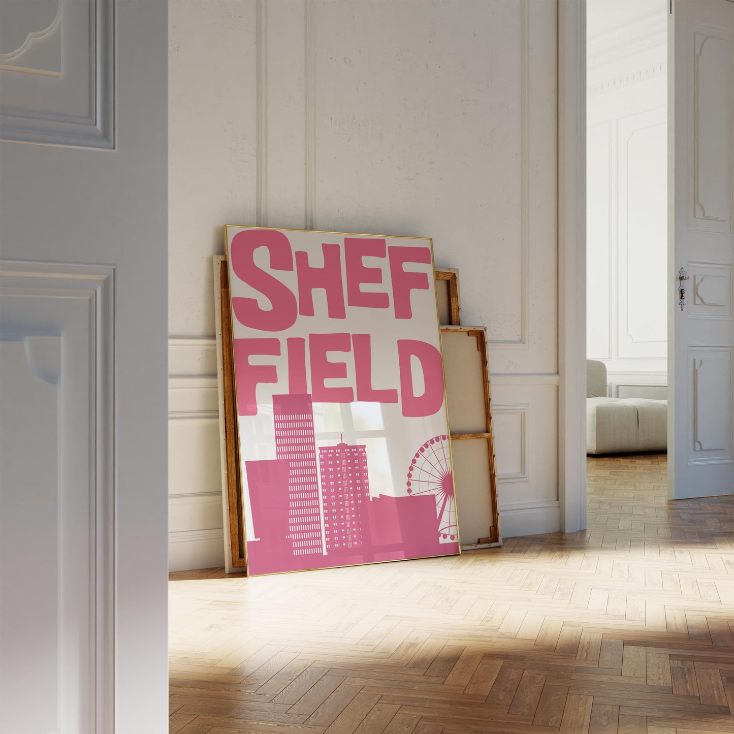 Framed artwork with 'SHEFFIELD' in pink text on a white background, leaning against a wall.