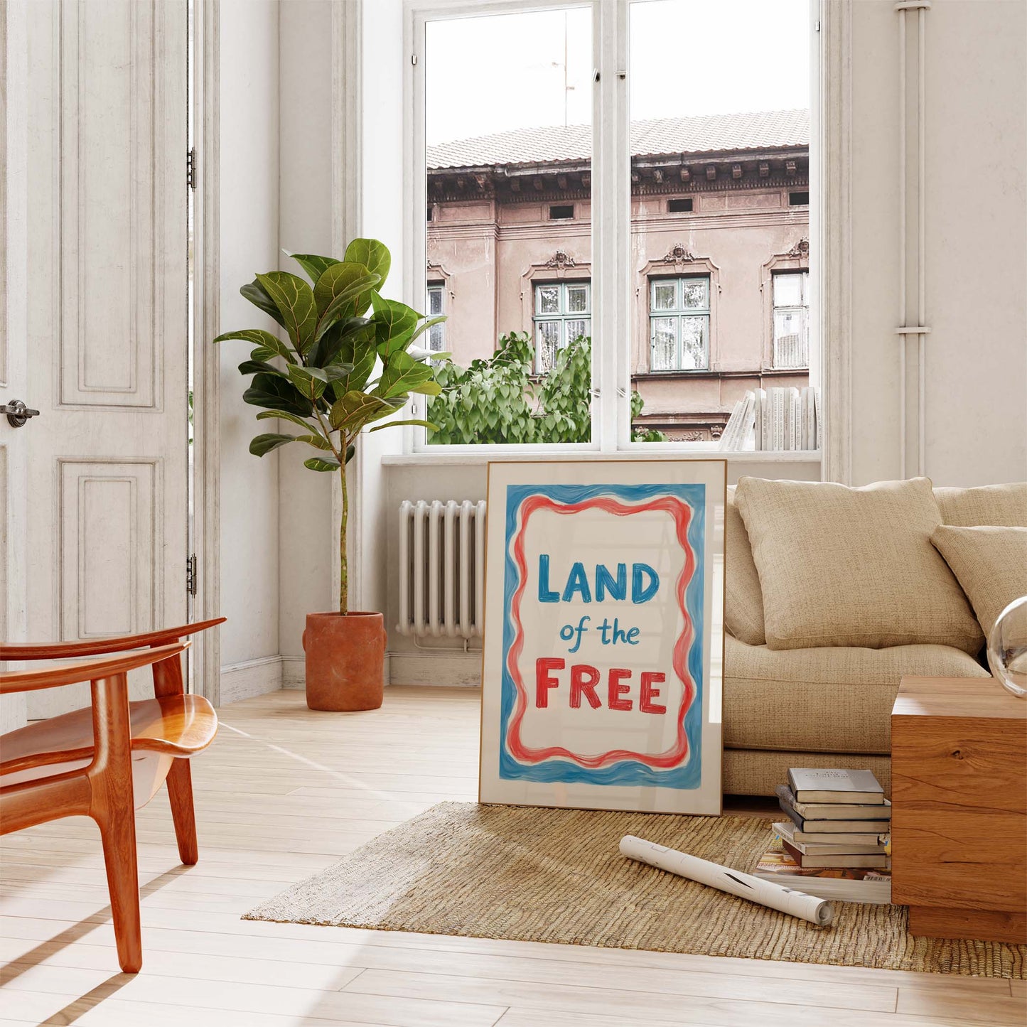A framed 4th of July print with the words 'Land of the Free' in blue text, surrounded by a wavy red and blue border.