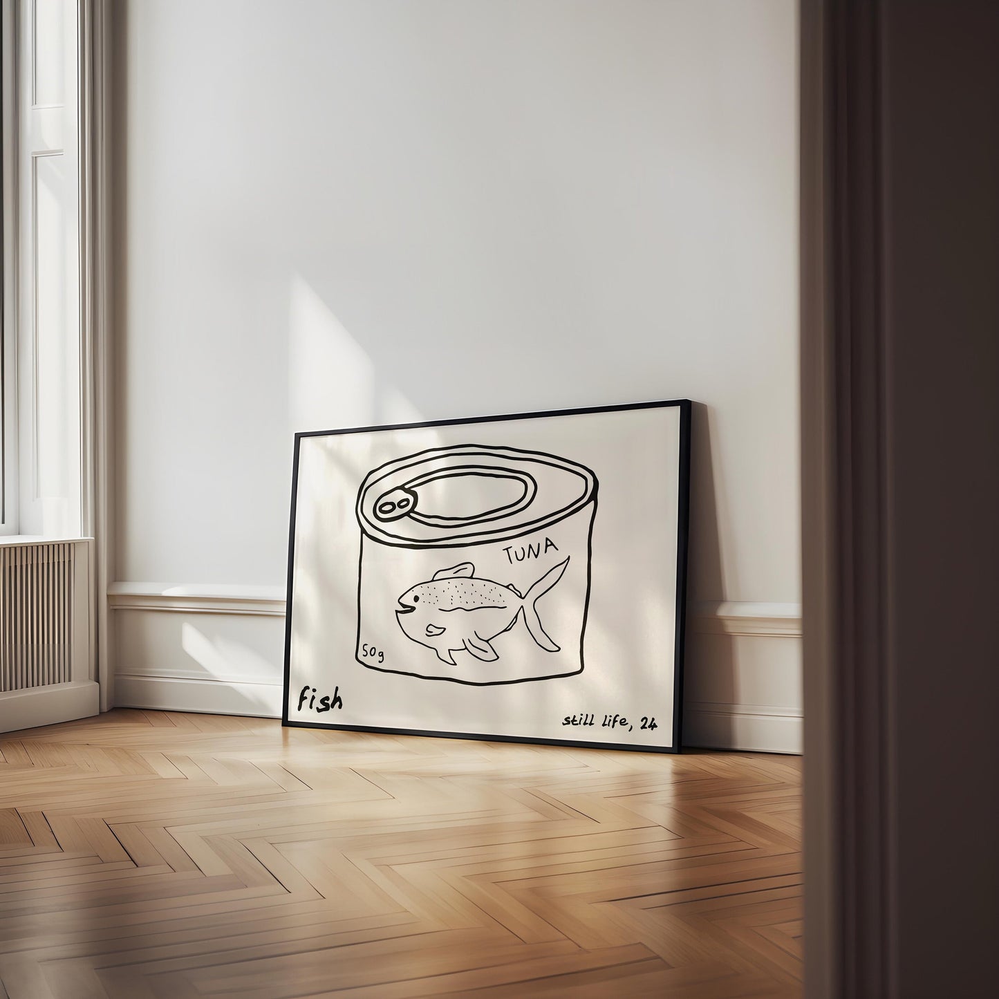 A minimalist line drawing of a tuna can, framed as kitchen wall art. The print includes the words 'fish' and 'still life'.