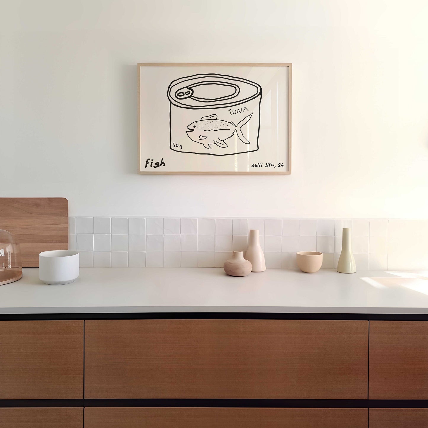 A minimalist line drawing of a tuna can, framed as kitchen wall art. The print includes the words 'fish' and 'still life'.