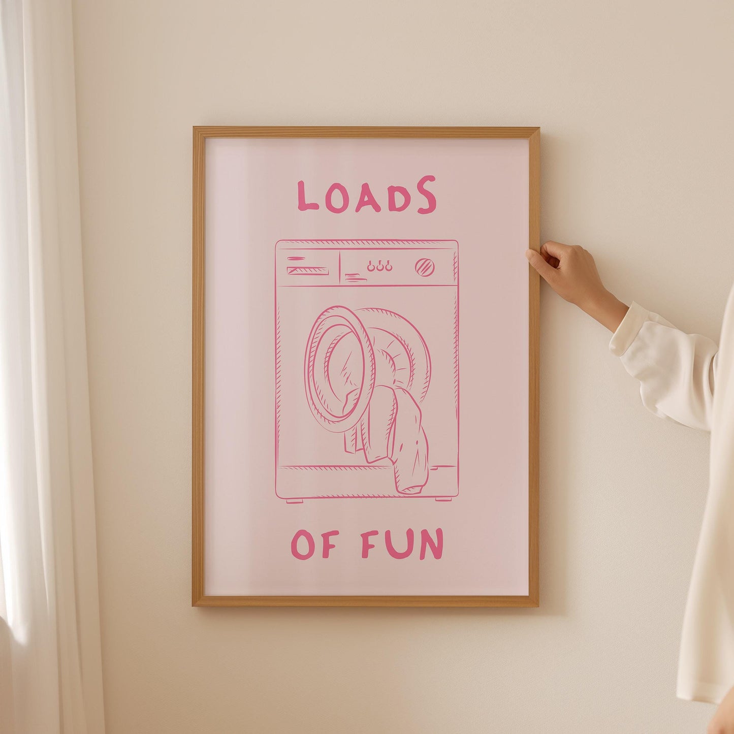Framed funny laundry room print with a pink washing machine illustration and the pun 'Loads of Fun' on a pink background.
