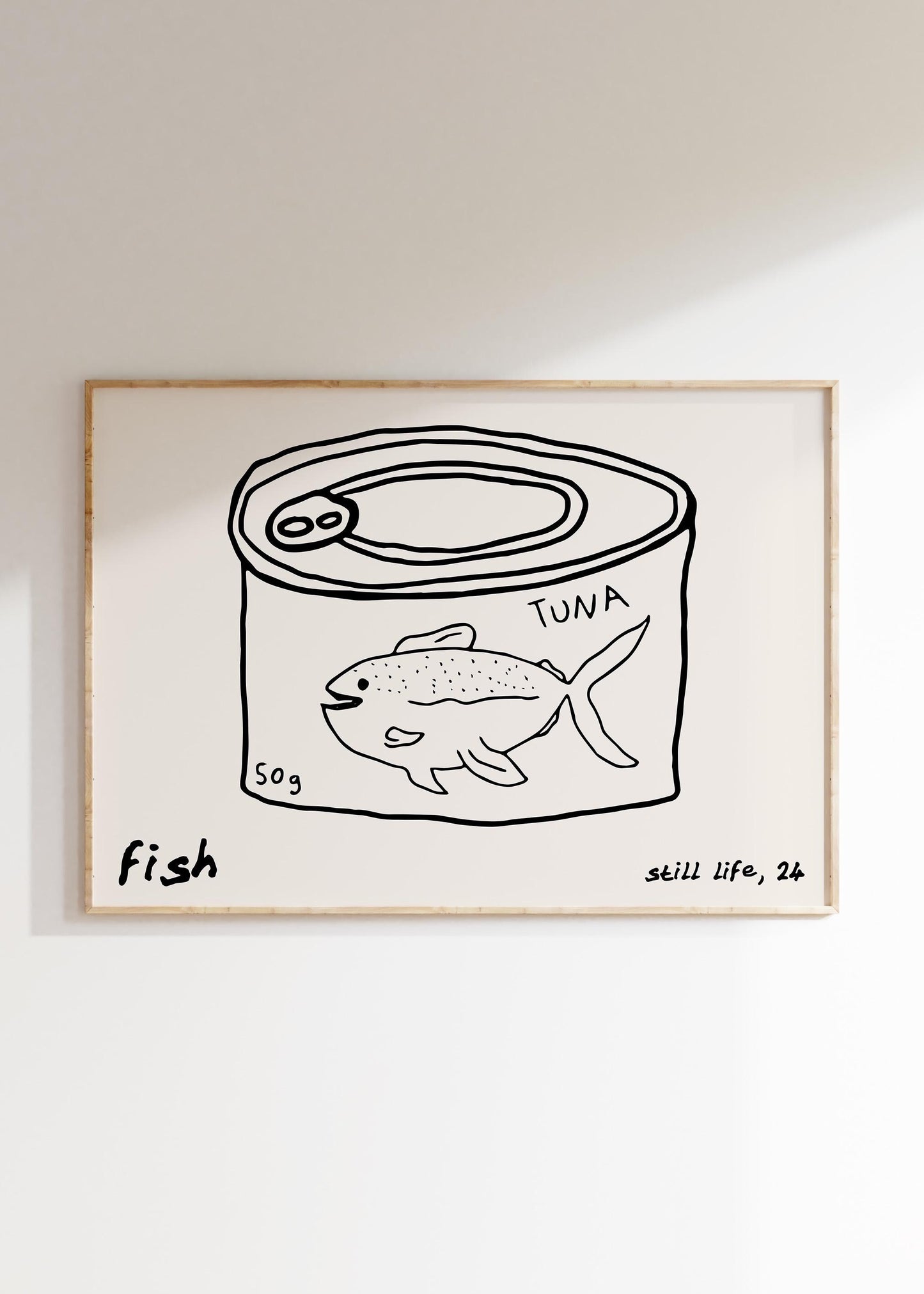 A minimalist line drawing of a tuna can, framed as kitchen wall art. The print includes the words 'fish' and 'still life'.