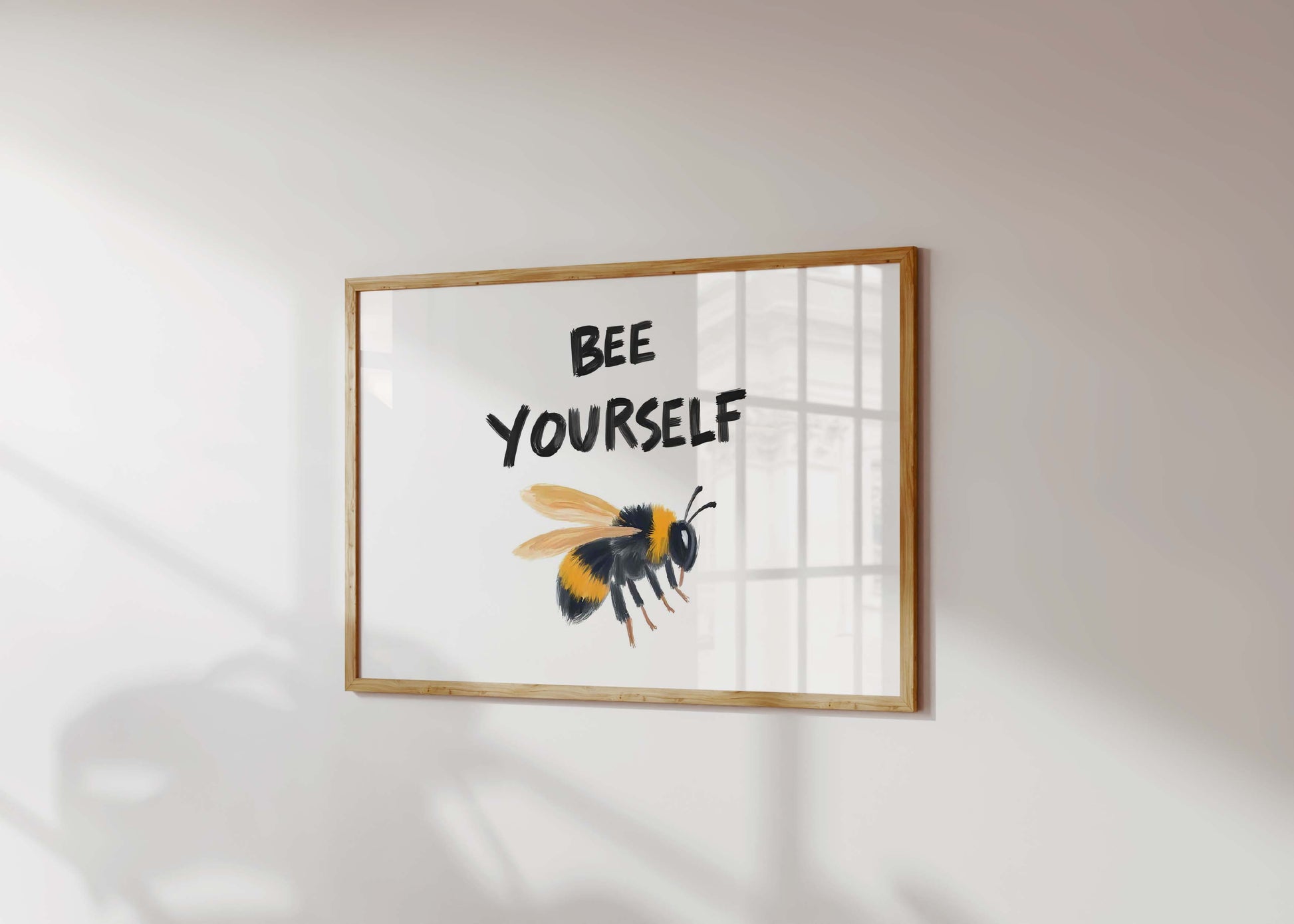 An inspirational bee print in a landscape frame, featuring a painterly bumblebee illustration under the quote 'Bee Yourself'.