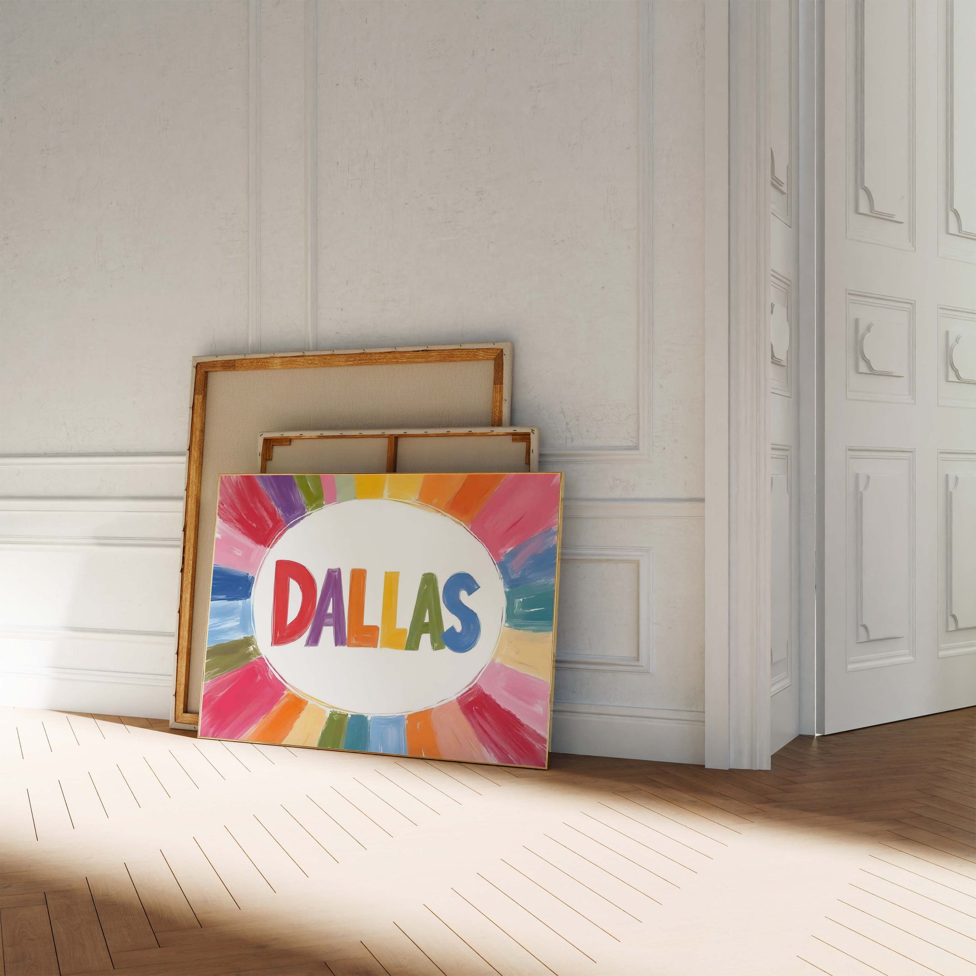 A colorful Dallas print in a landscape frame, with the word 'DALLAS' in rainbow letters surrounded by a painterly sunburst of color.
