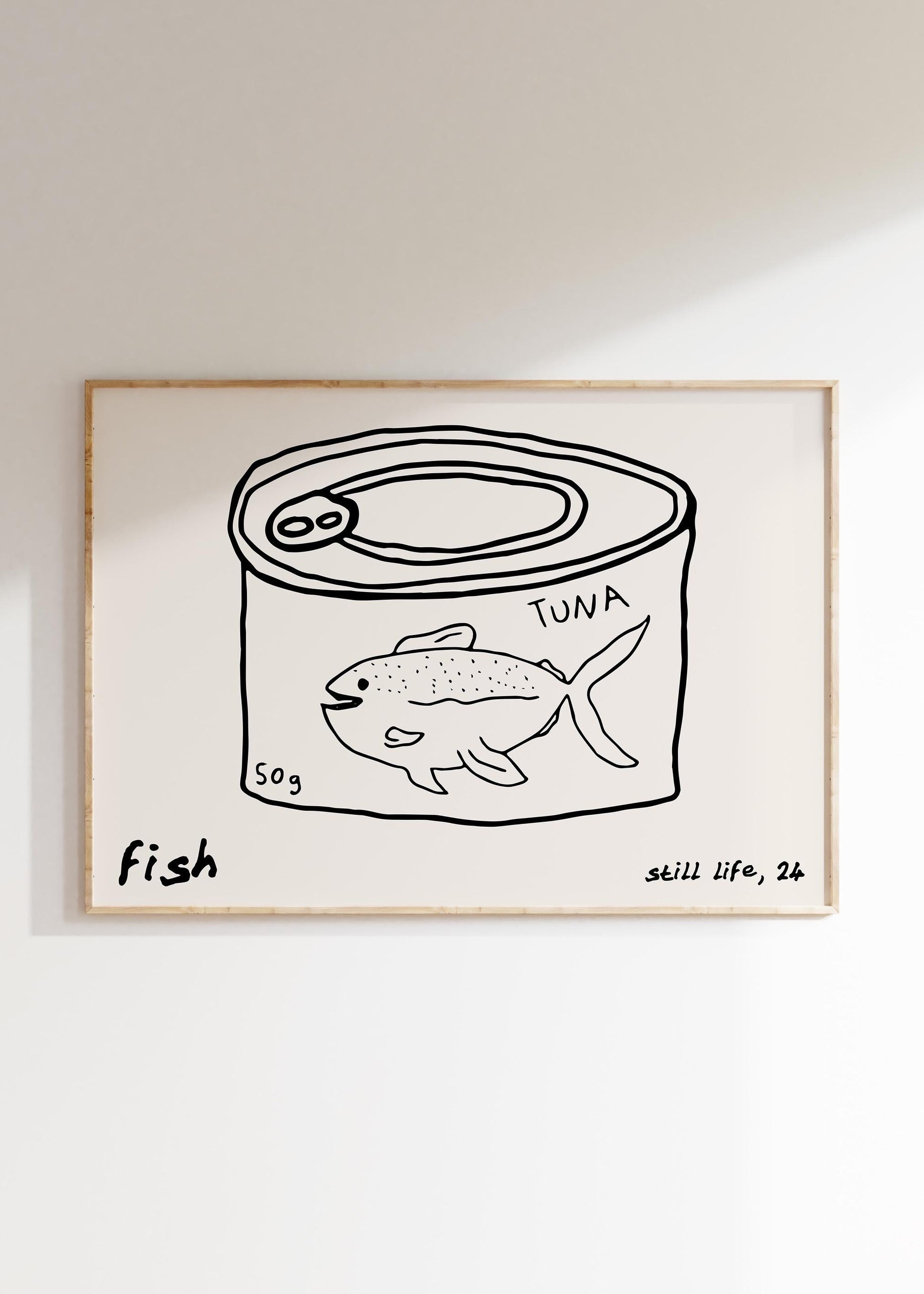 A minimalist line drawing of a tuna can, framed as kitchen wall art. The print includes the words 'fish' and 'still life'.