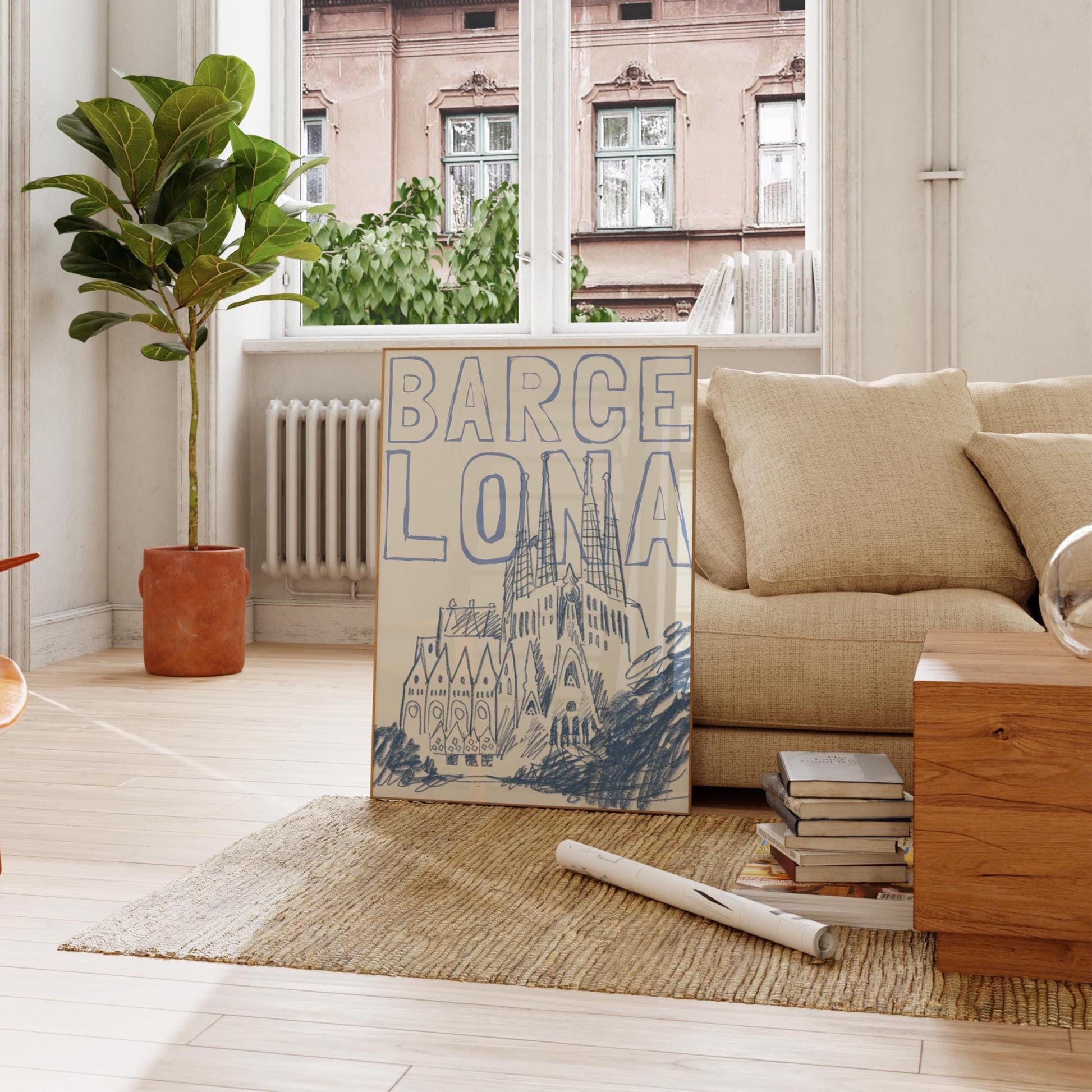 A Barcelona travel poster in a wood frame, with a blue sketch of the Sagrada Familia and the word 'BARCELONA' in a block font.