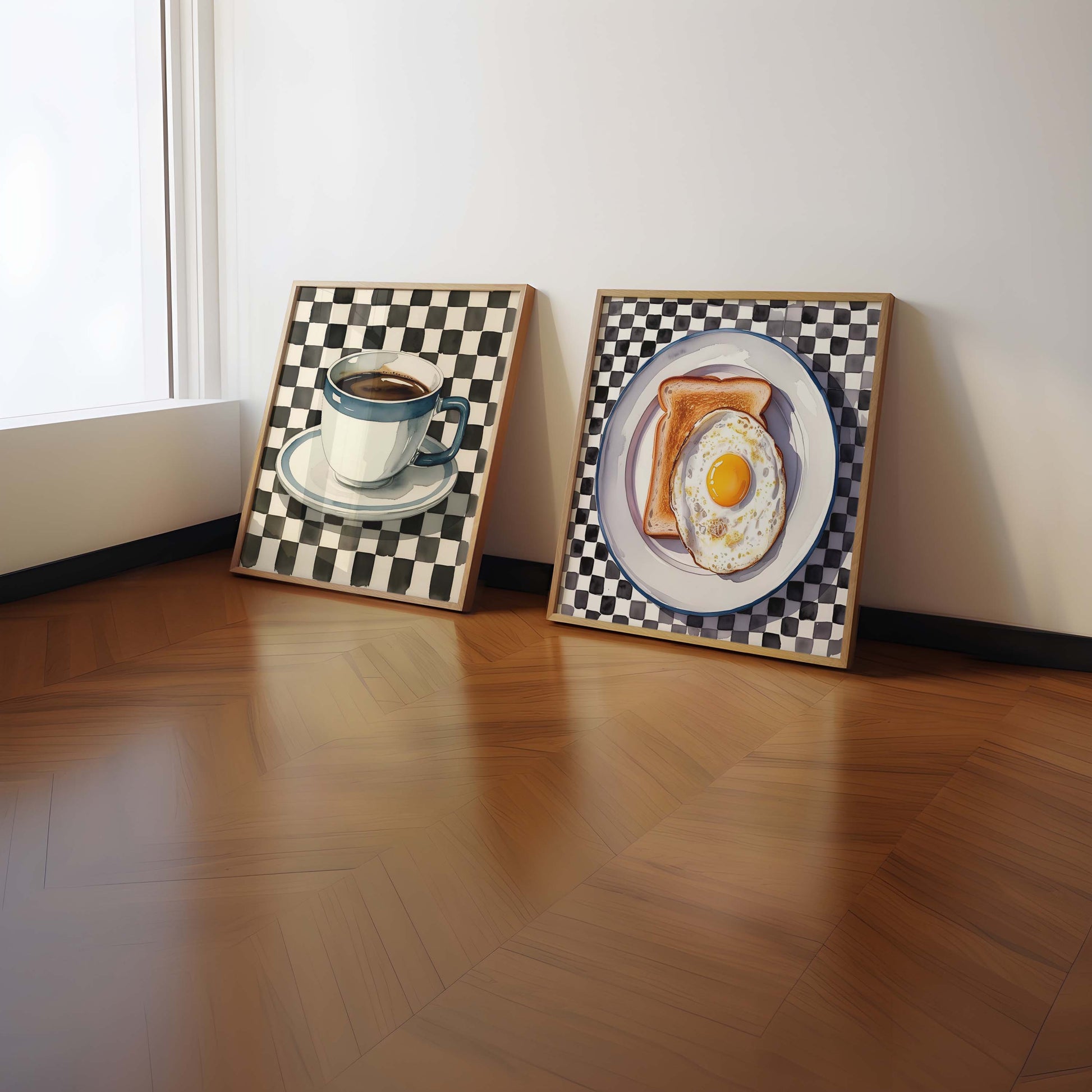 Two framed paintings of a coffee cup and saucer, and a plate with toast and egg on a wooden floor.